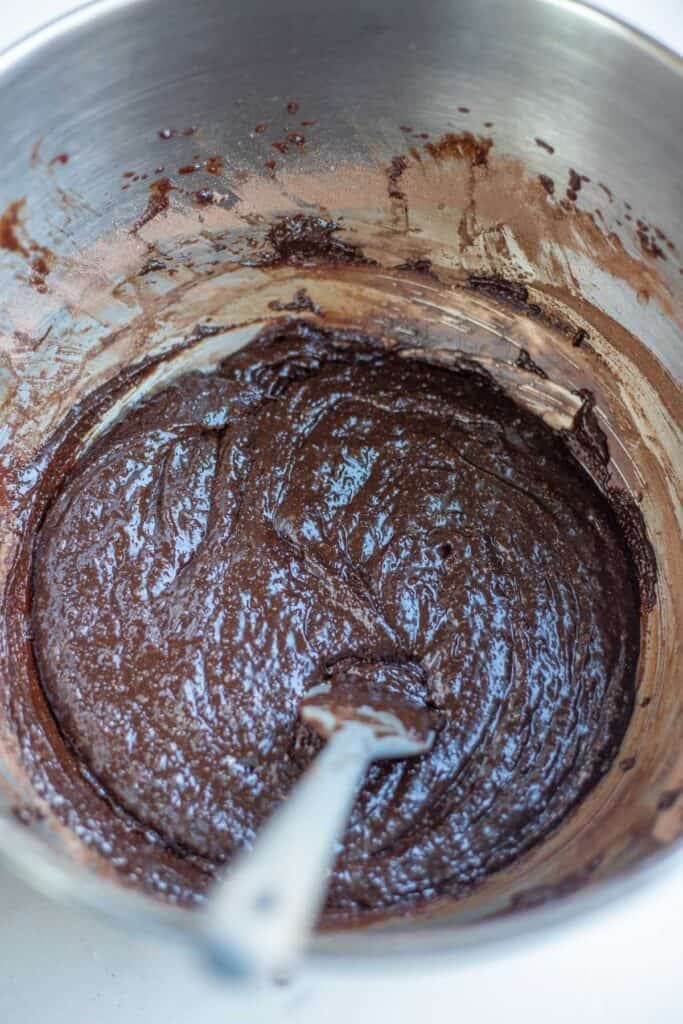 Whole wheat brownie batter in a mixing bowl with a silicone spatula.