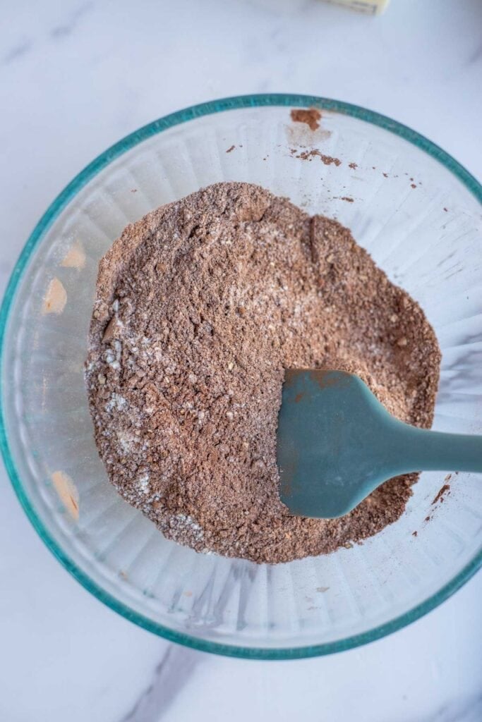 Cocoa powder and freshly milled flour stirred together in a glass mixing bowl.