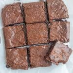 A dish of brownies cut into 9 even squares on the marble counter top.