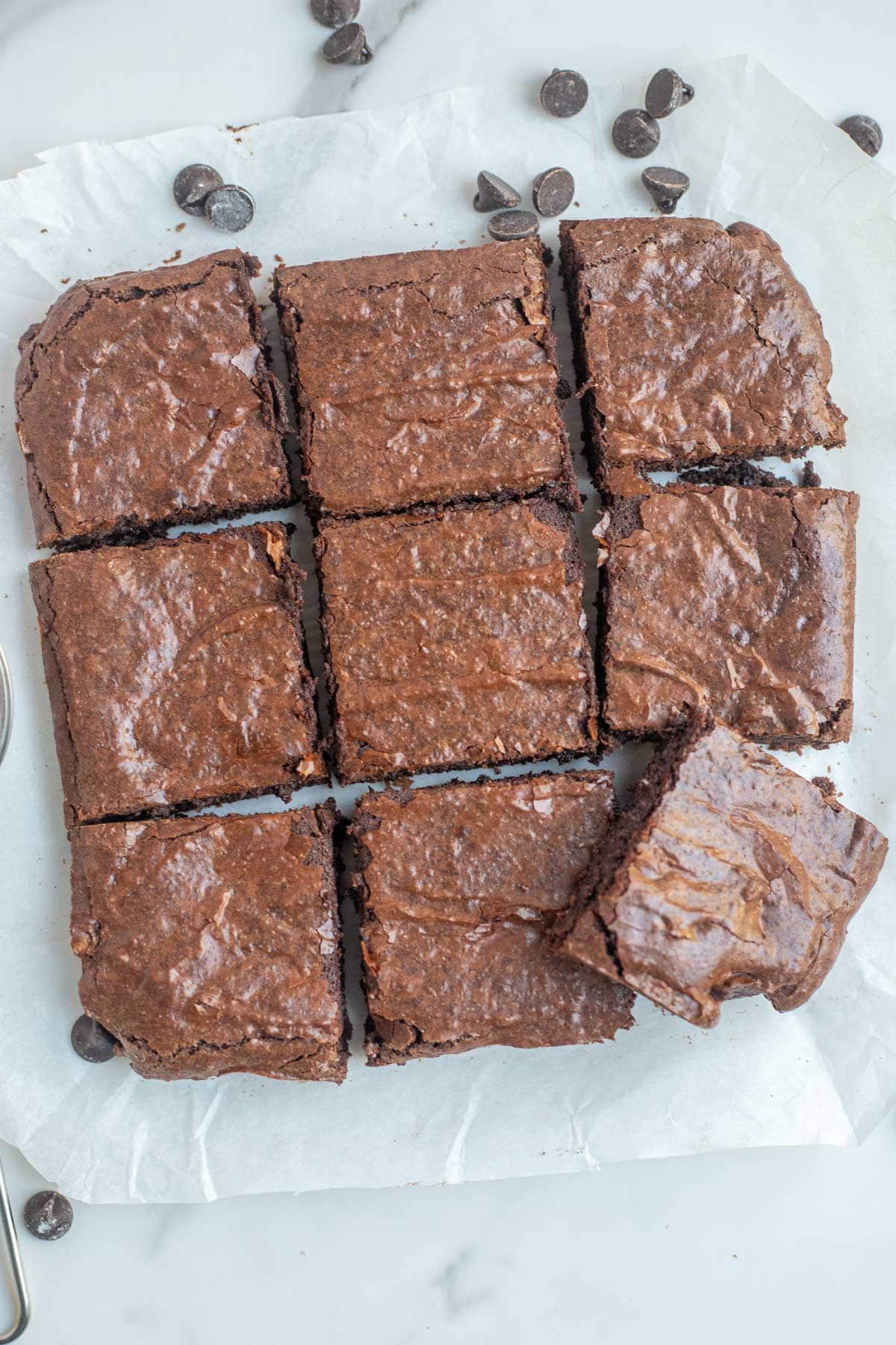 A dish of brownies cut into 9 even squares on the marble counter top.