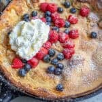 a freshly milled dutch baby pancake topped with berries and whipped cream.