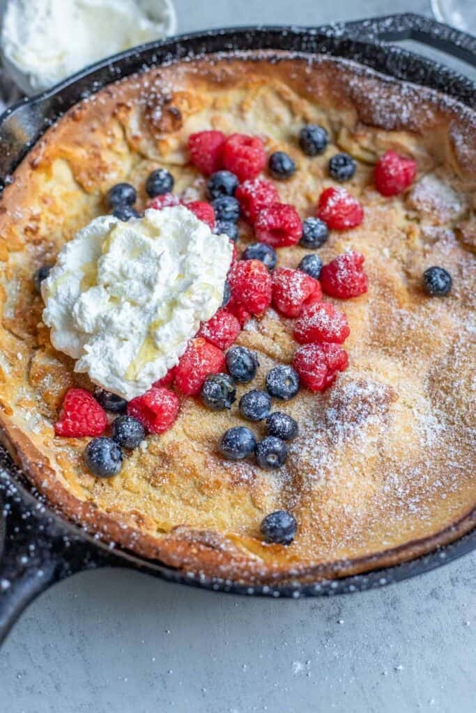 a freshly milled dutch baby pancake topped with berries and whipped cream.