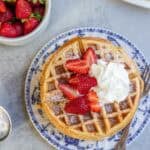 an overhead view of whole wheat waffles topped with whipped cream and strawberries.