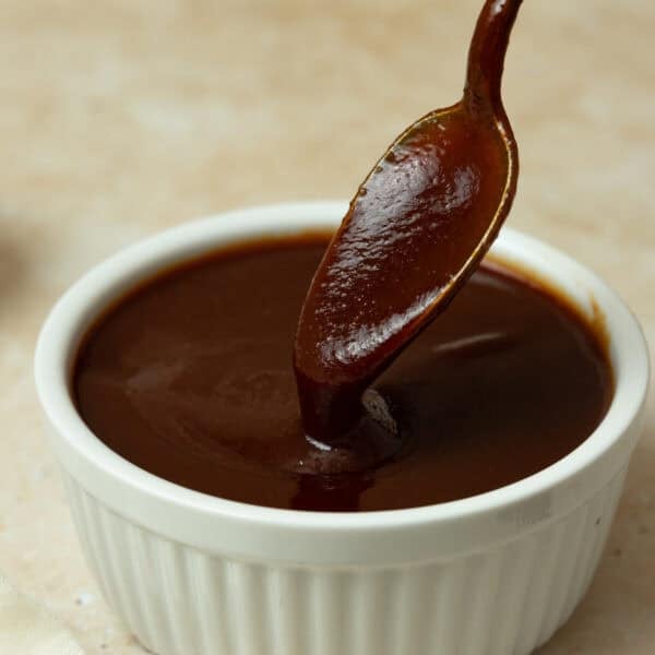 A bowl of barbecue sauce with a spoon dipped in it.