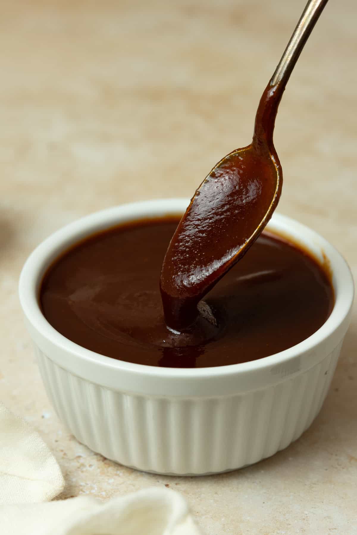 A bowl of barbecue sauce with a spoon dipped in it.