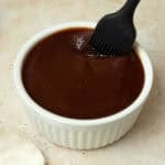 A bowl of sauce with a pastry brush.