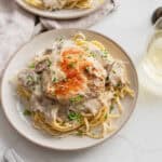 pasta on a serving plate covered in a mushroom cream sauce and topped with a cooked chicken breast.
