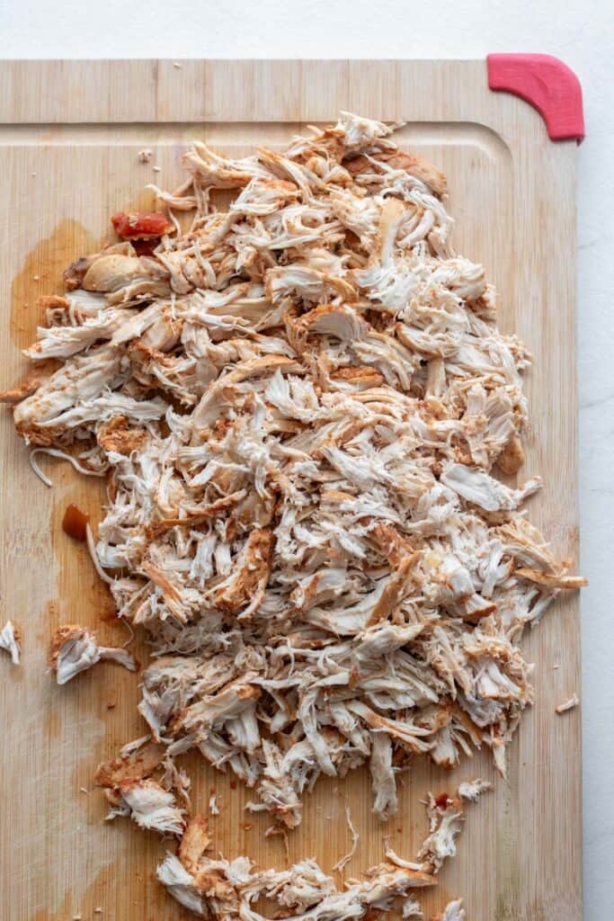 Chicken shredded on a cutting board.