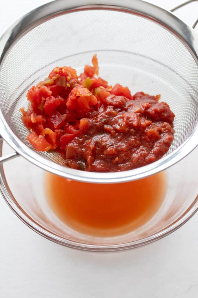 Salsa and diced tomatoes in a mesh strainer over a bowl.