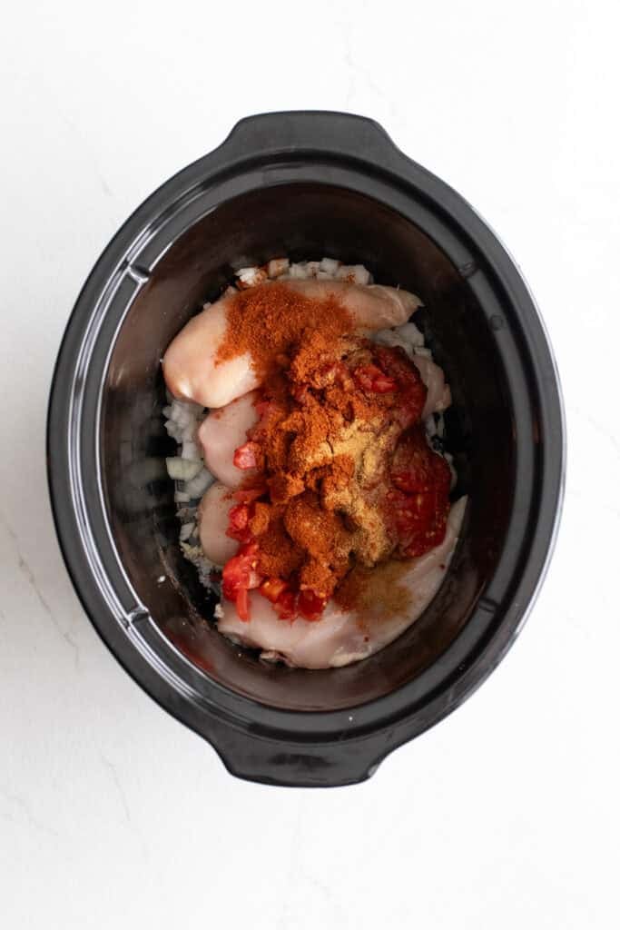 Chicken breasts in a crockpot topped with seasoning.