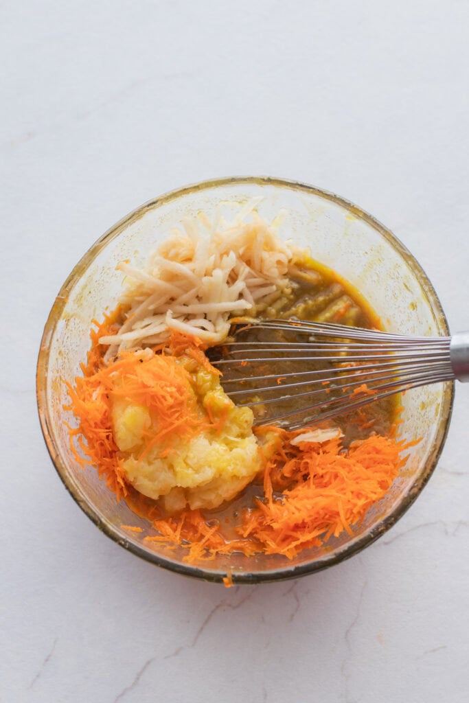 Brown sugar, grated carrot, and crushed pineapple mixed together in a glass bowl.