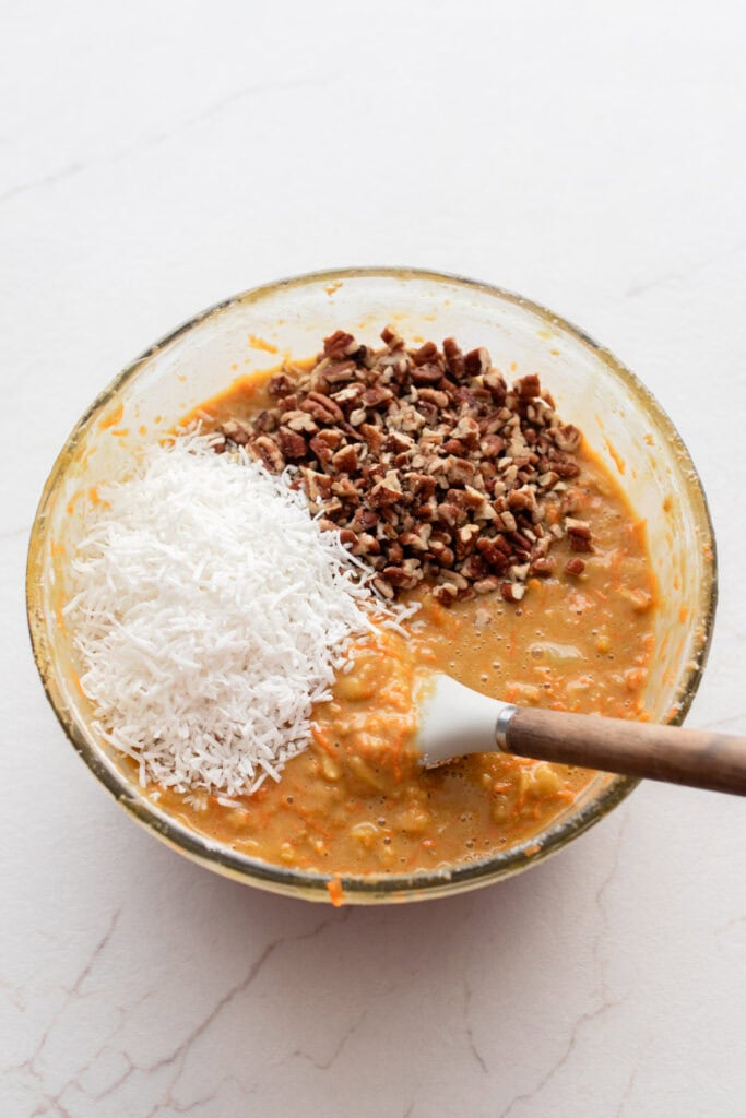 Dry muffin ingredients mixed with wet muffin ingredients and topped with nuts and shredded coconut.