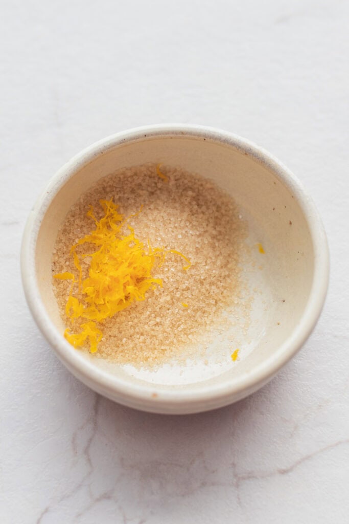 Turbinado sugar and orange zest in a mixing bowl combined.