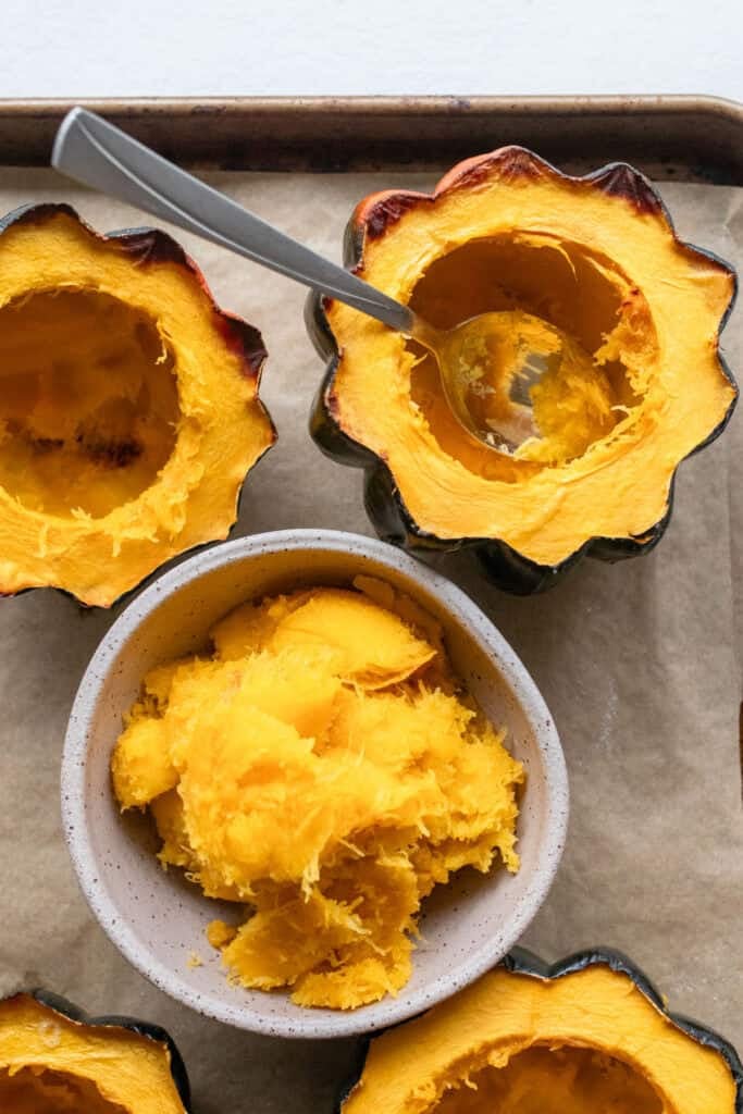 Acorn squash scooped out and the squash flesh in a bowl.