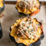 Stuffed acorn squash on a baking sheet.