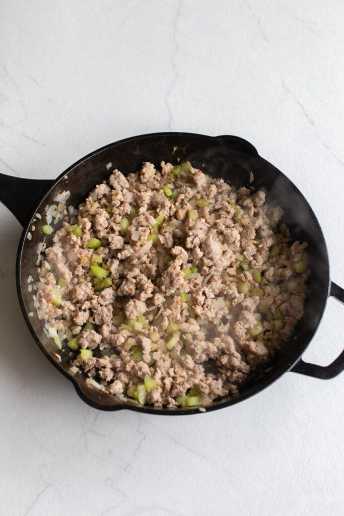 Sausage added to other ingredients in cast iron skillet.