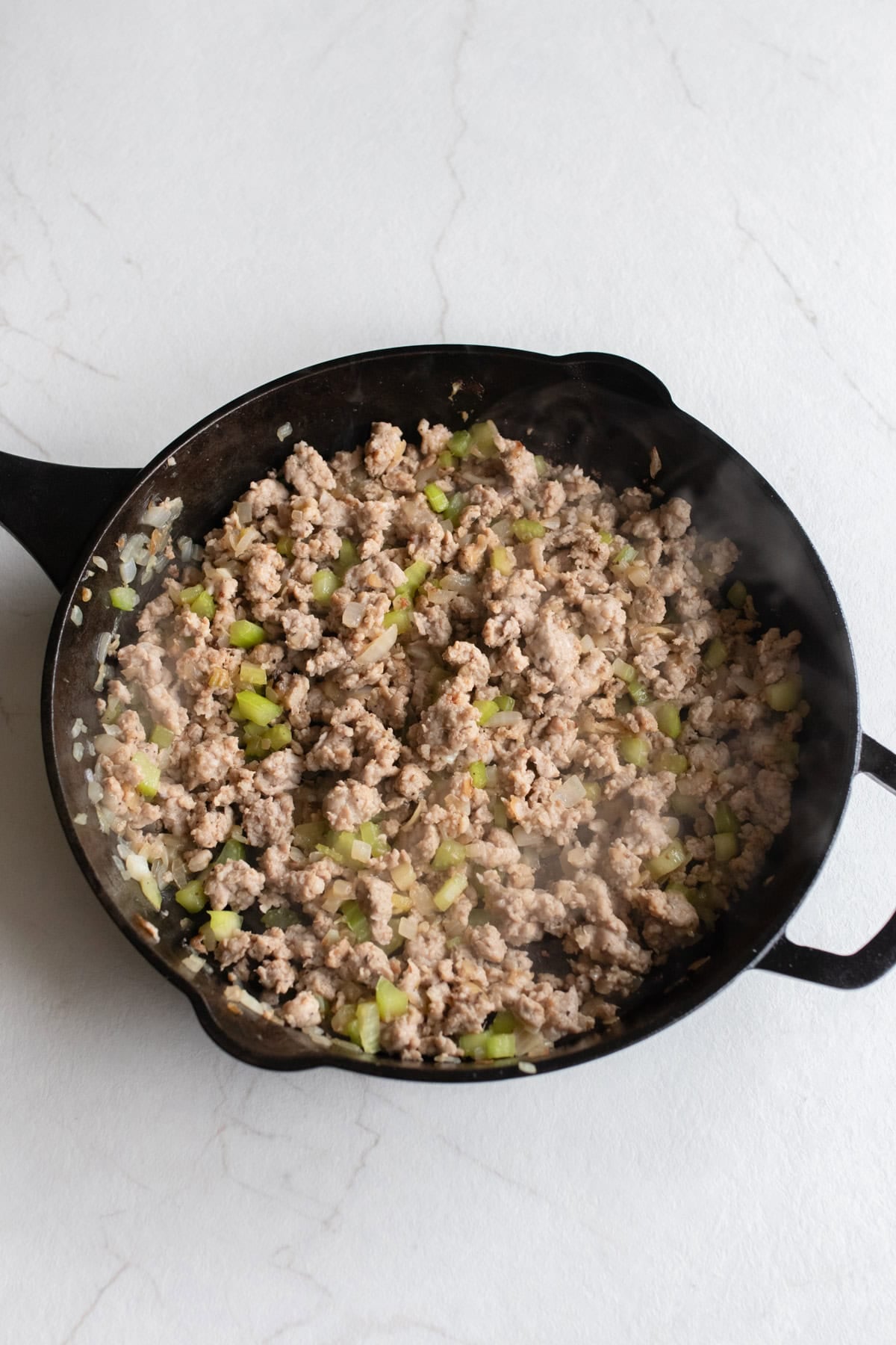 Sausage added to other ingredients in cast iron skillet.