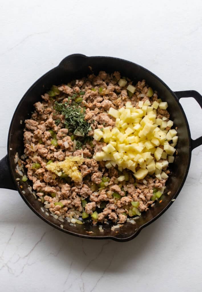 Apples and sage added into cast iron skillet.