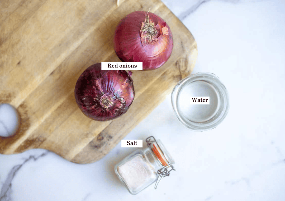 Red onions, water, and salt on a wooden cutting board.