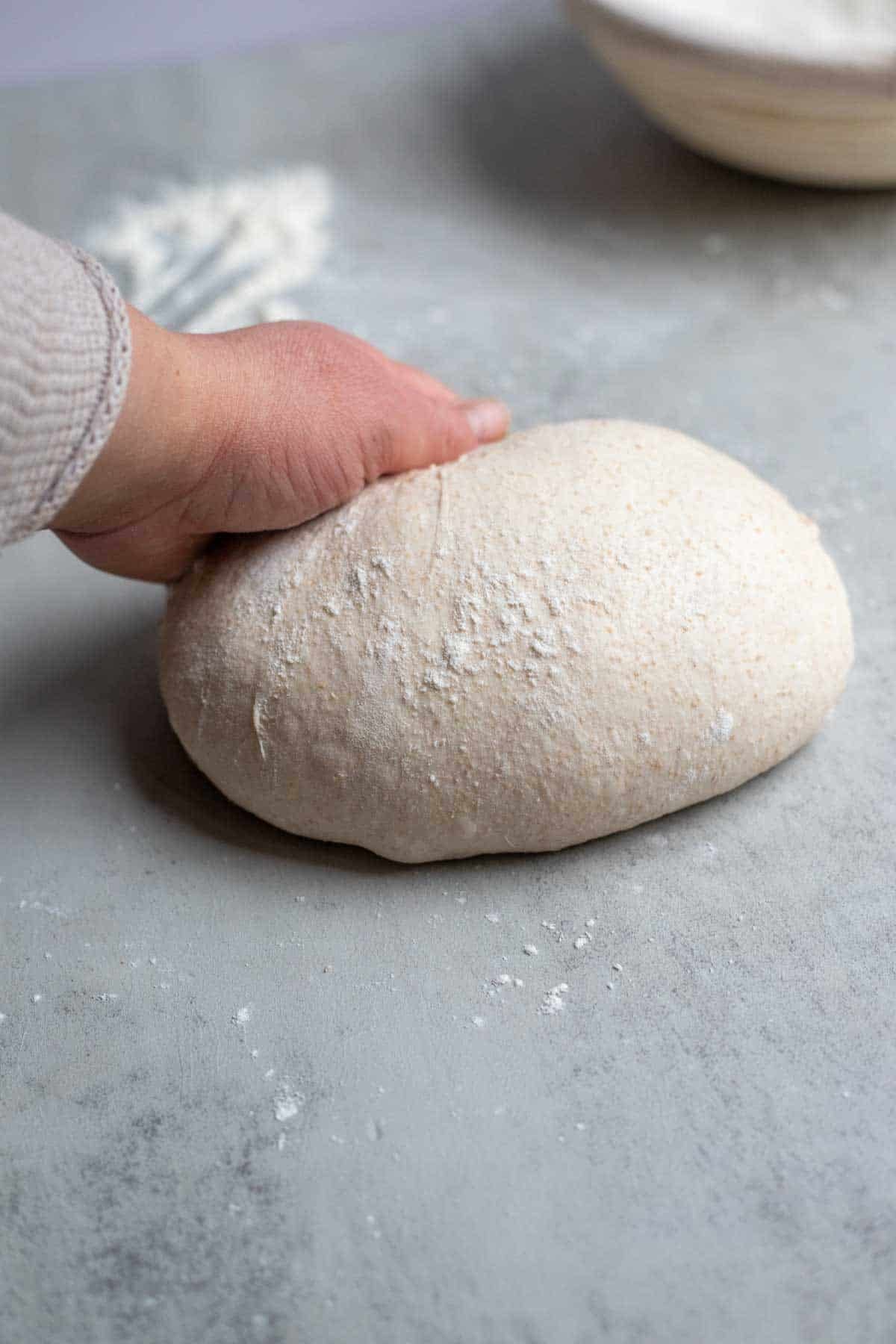 Spelt sourdough shaped into a ball on the kitchen counter.