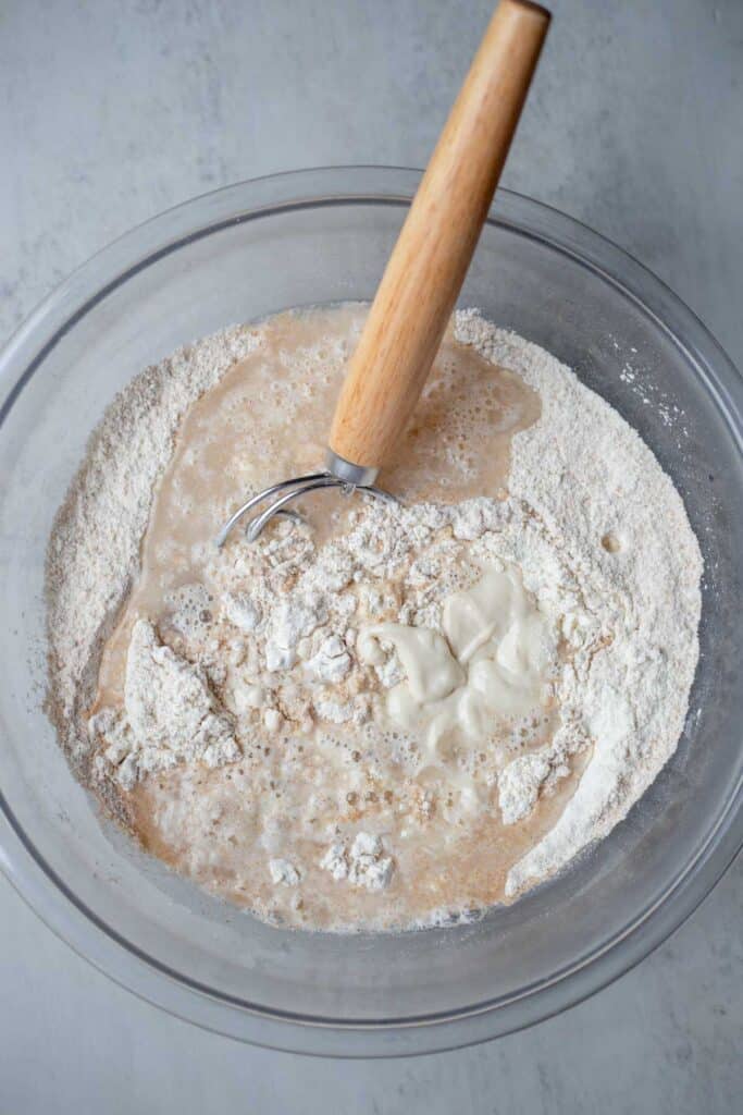 Bread flour, spelt flour, salt, water, and sourdough starter combined in a glass bowl.
