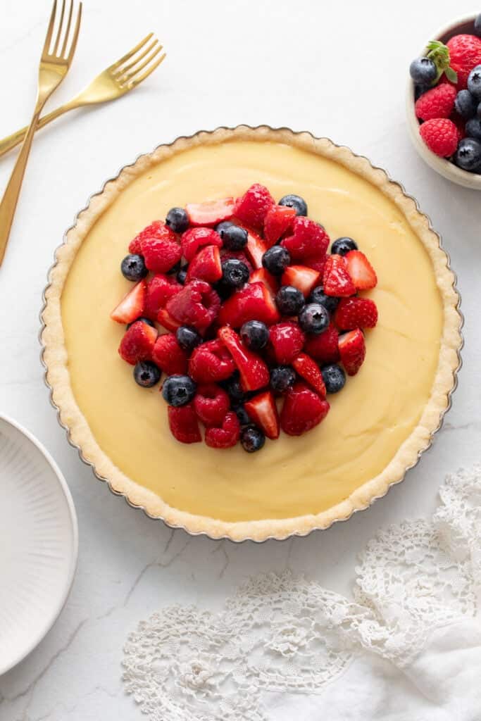 A custard in a tart pan topped with fresh berries.