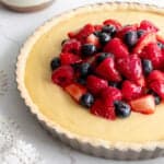 a tart pan filled with a white chocolate custard topped with a mixed berry compote.