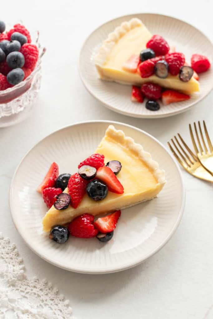 two slices of berry tart on small white dessert plates.