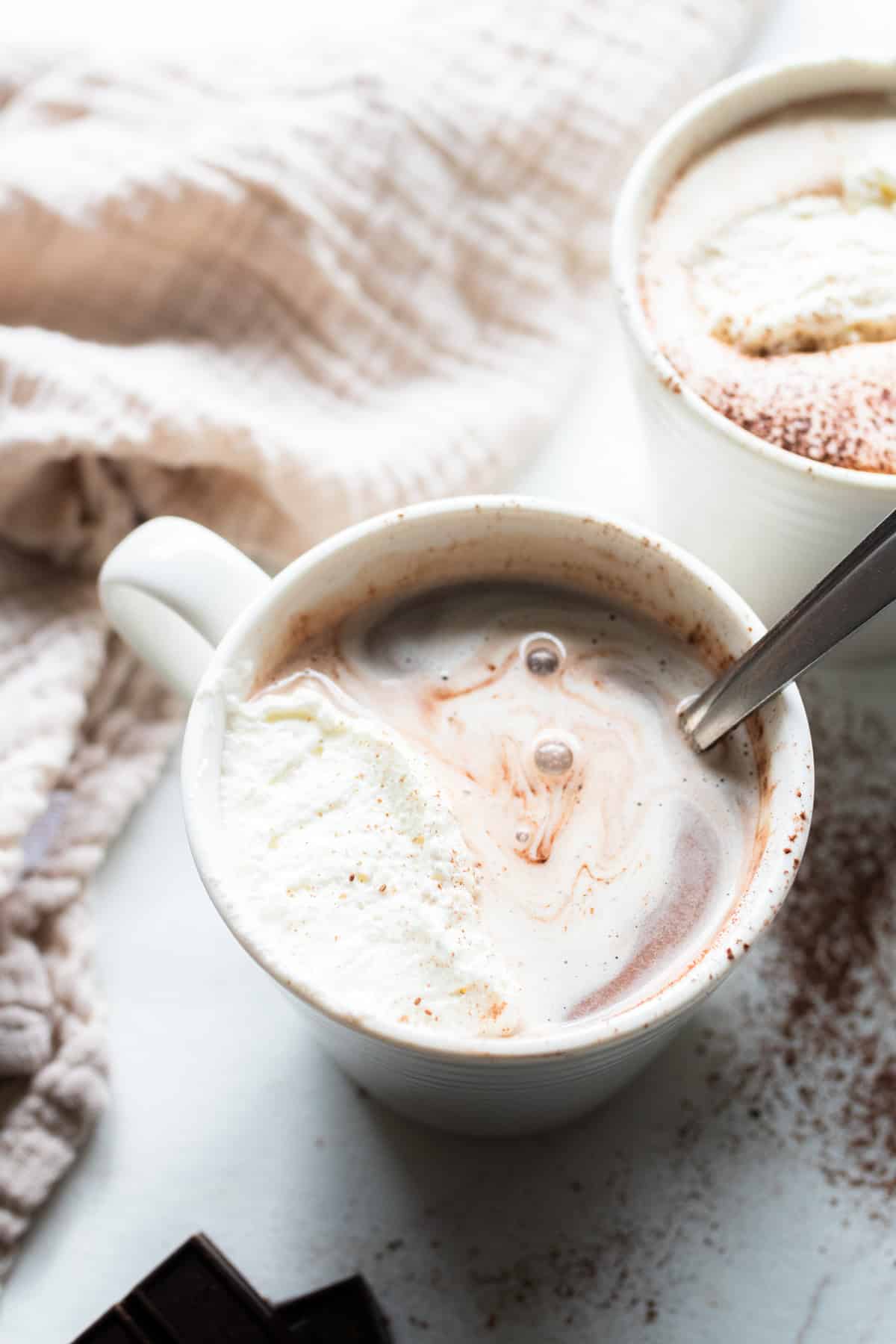 A white mug filled with bone broth hot chocolate and topped with home made whipped cream.