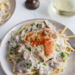 pasta on a serving plate topped with a mushroom cream sauce and a cooked chicken breast.