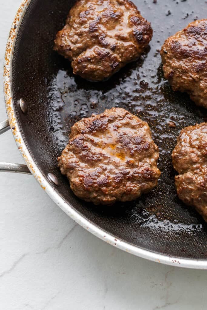 Cooked sausage patties in a skillet.