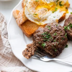 A plate with eggs and a sausage patty.