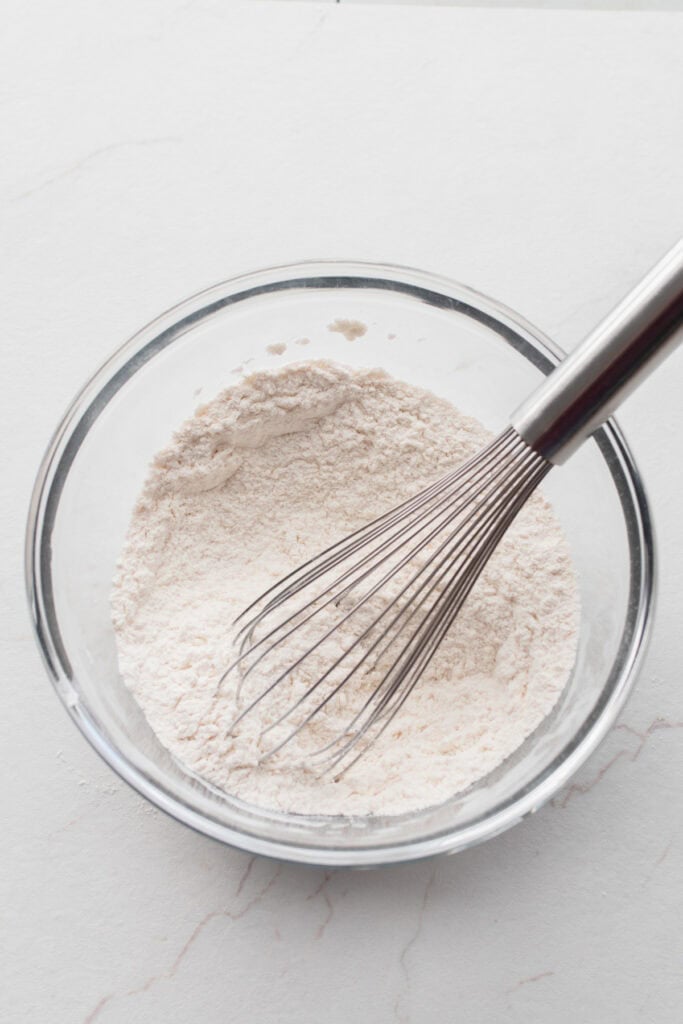 Dry ingredients in a bowl with a whisk.
