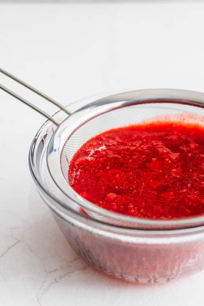 Sauce strained through a strainer into a bowl.