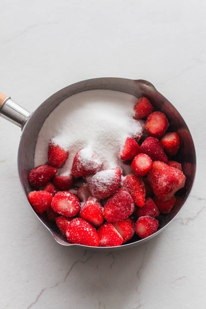 Strawberries and sugar in a sauce pan.