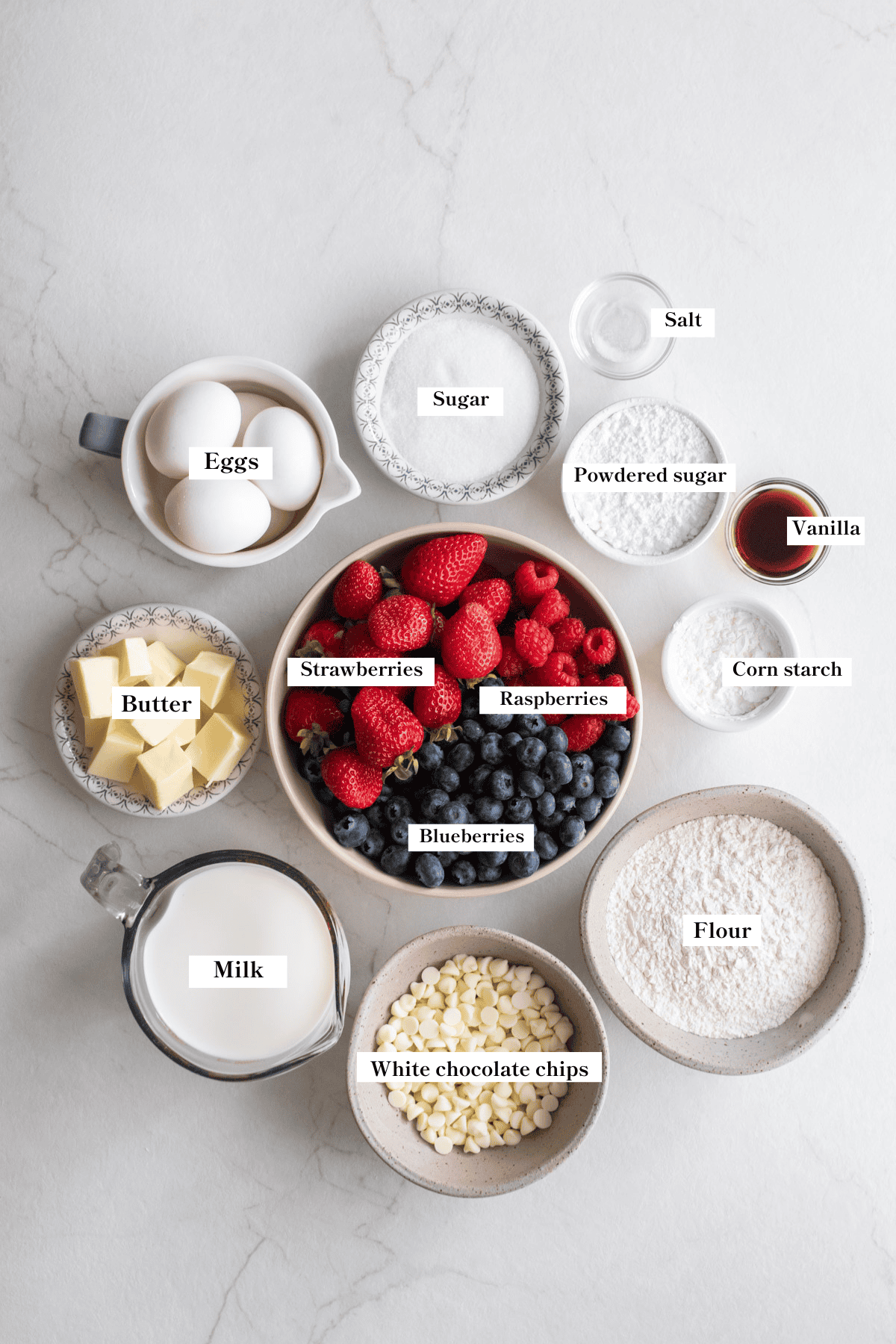 Ingredients for triple berry tart in bowls on a counter.