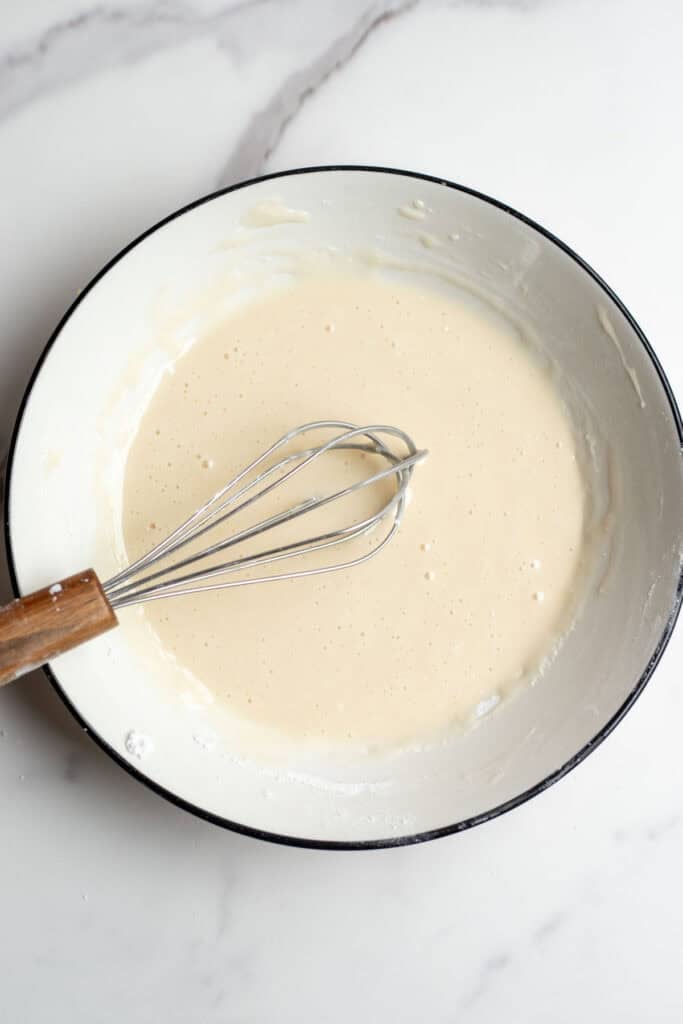 Icing glaze in a bowl with a whisk.
