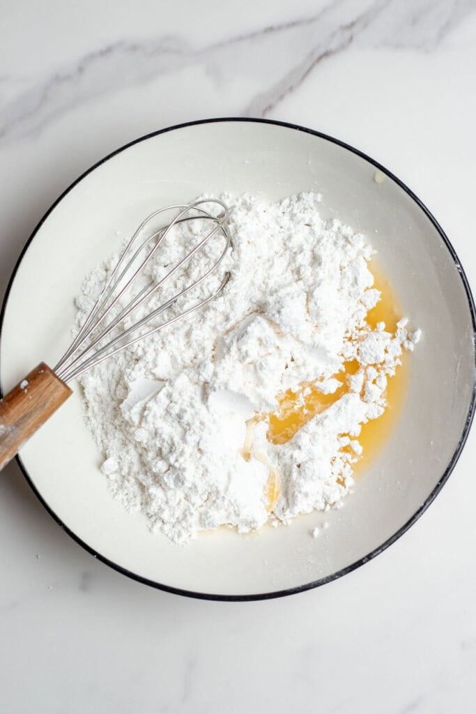 Powdered sugar in a bowl with orange juice poured in.