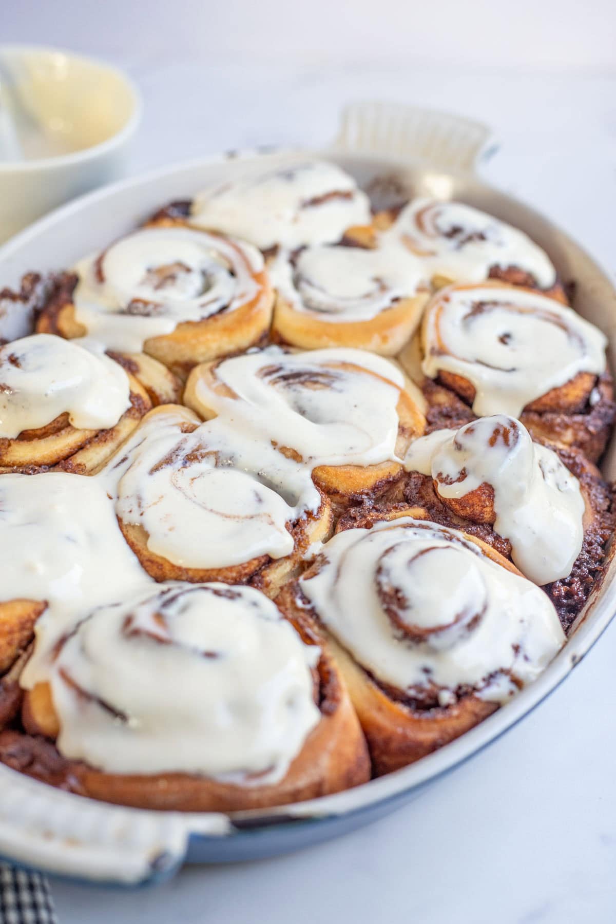 A casserole dish filled with cream cheese frosted cinnamon rolls.