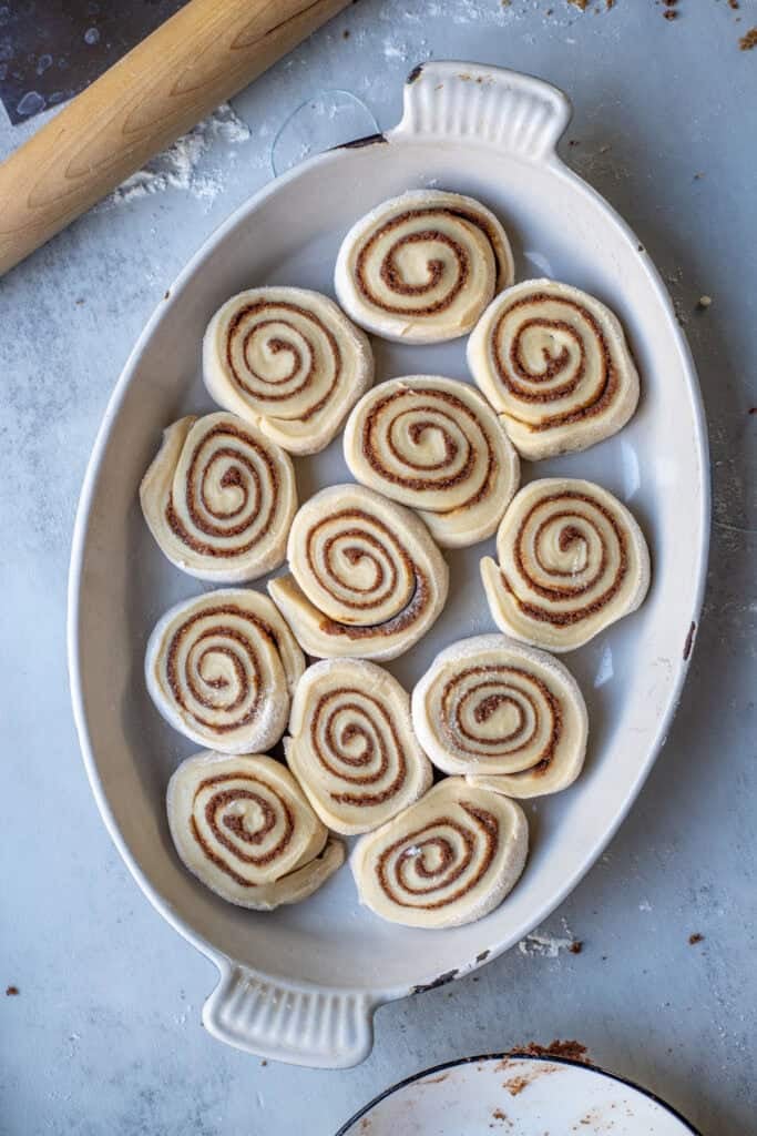 12 uncooked cinnamon rolls placed in a baking dish.