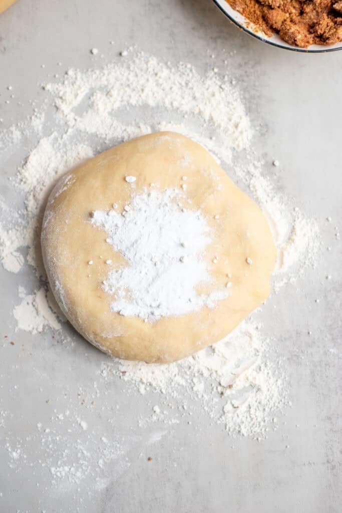 Baking soda and baking powder piled on top of a ball of dough.