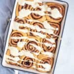 Cinnamon rolls with a frosting in a pan.