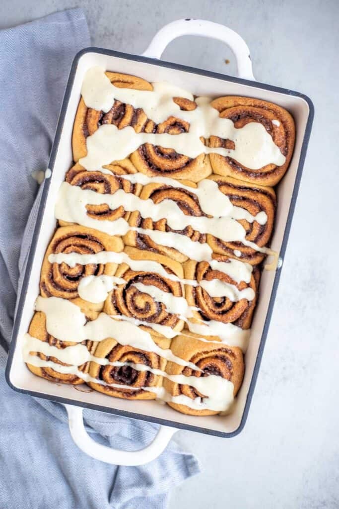 Cinnamon rolls with a frosting in a pan.