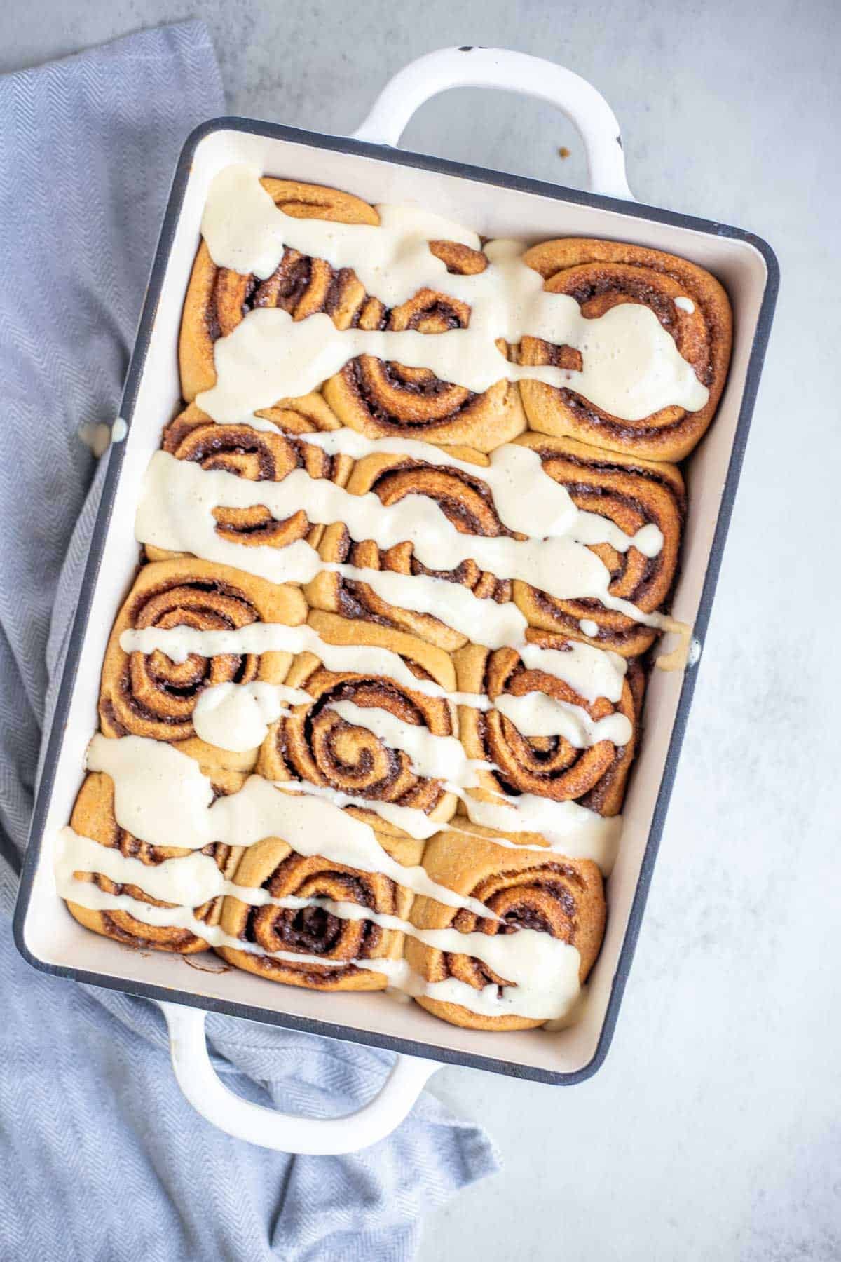 Whole wheat cinnamon rolls with frosting in a pan.