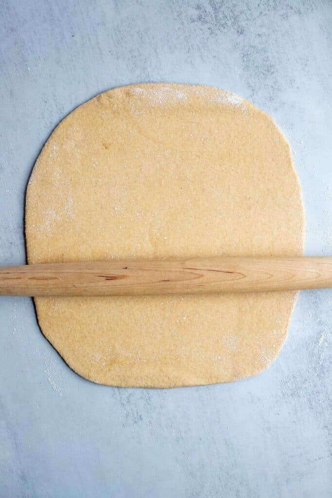 Dough rolled out into a rectangle with a rolling pin on top.