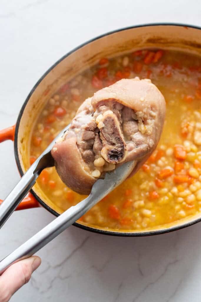 Removing the ham hock from a soup pot.