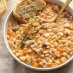 Ham and beans in a bowl with a slice of bread.