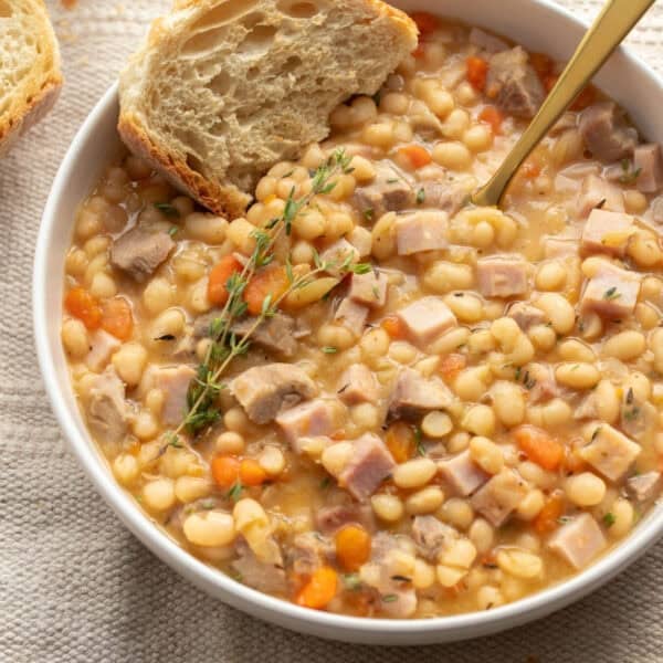Ham and beans in a bowl with a slice of bread.