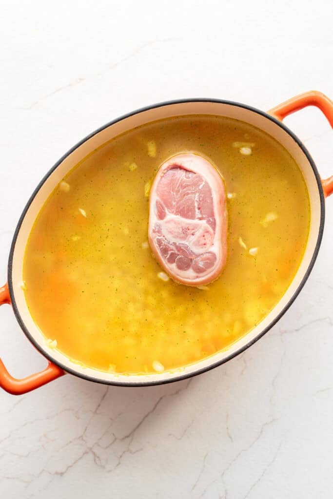 Broth and ham hock added to a Dutch oven.