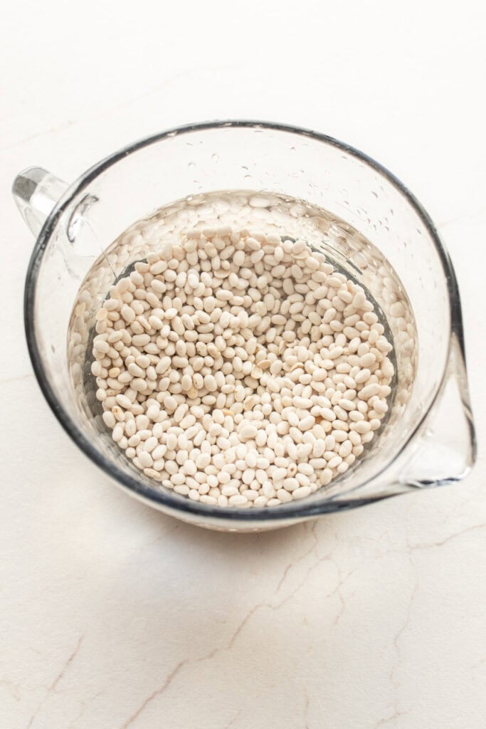 Beans in a glass bowl full of water.